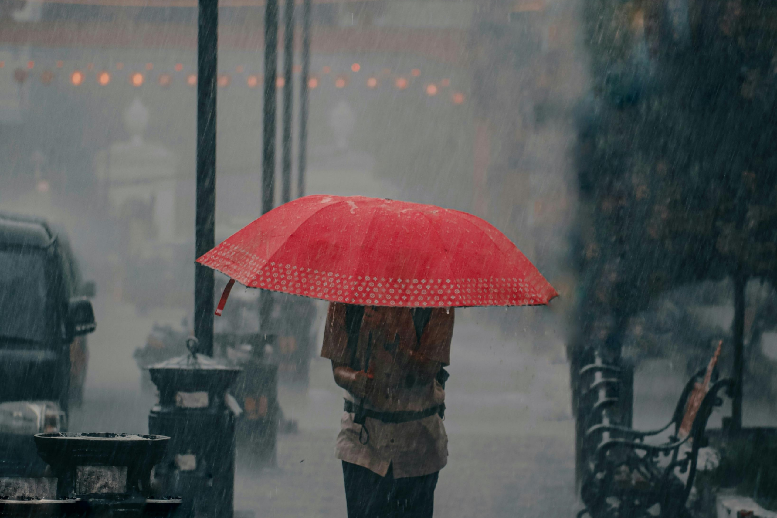 man with red umbrella in rainstorm